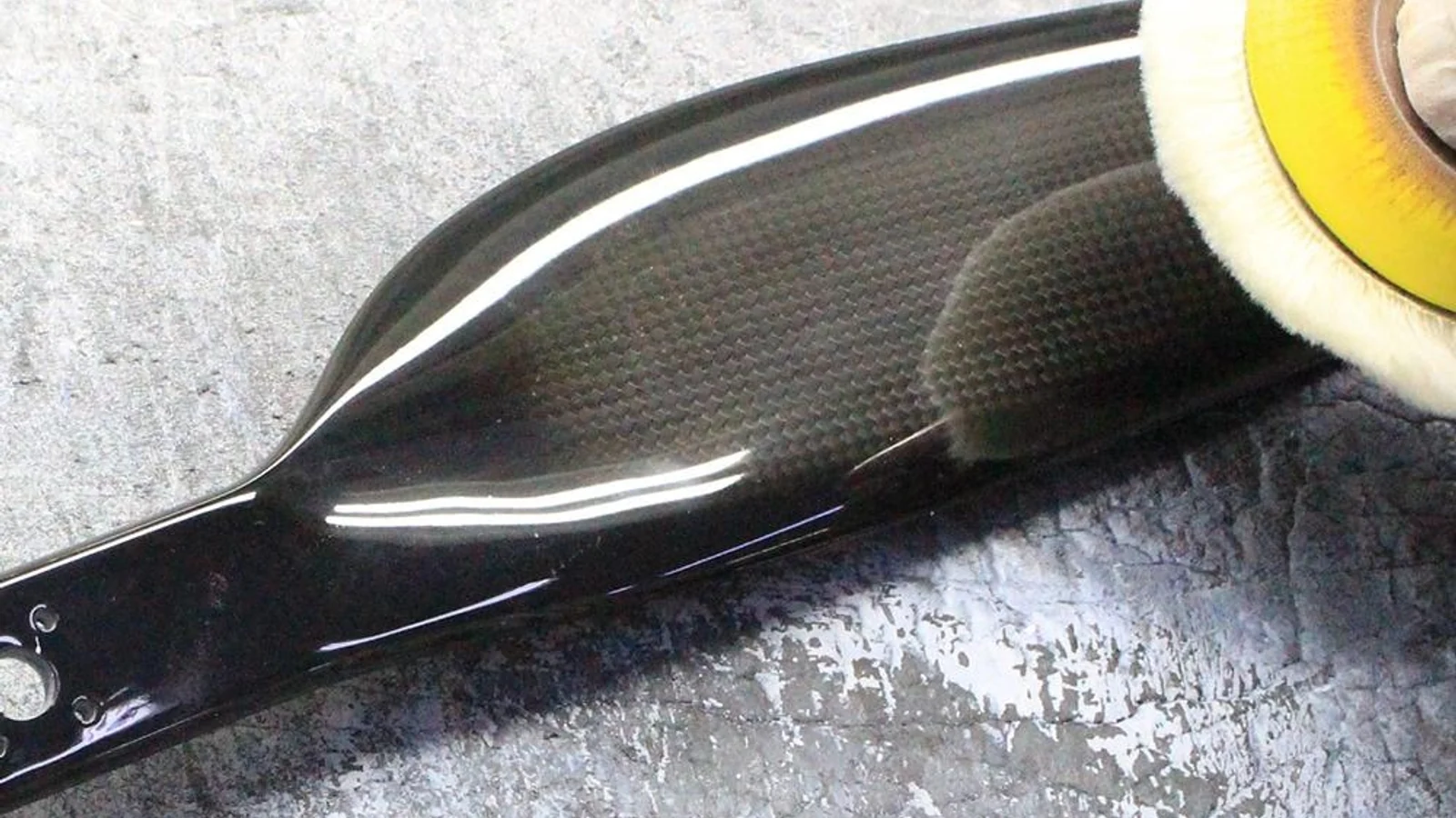 A polishing wheel running along the gloss surface of a finished carbon fiber blade